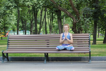 girl with curly blond hair practices yoga in the park
