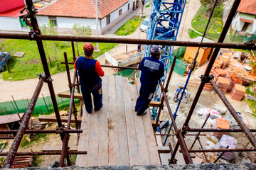 Workers are watching construction site from above, standing on scaffold