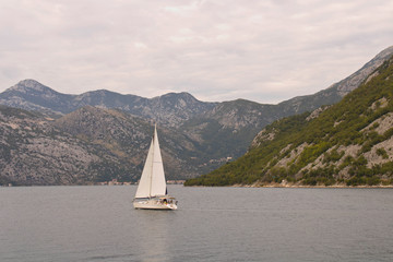 Naklejka premium Sailing yacht in the sea Bay on the background of the mountains.