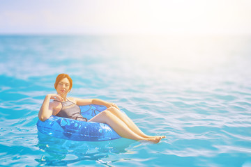 Beautiful young woman relax on inflatable ring make water splash in sea water with sunlight