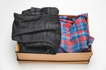 Clothes in a card box on a white background. Charity Help for people in need - box with donation clothes - Donation concept.