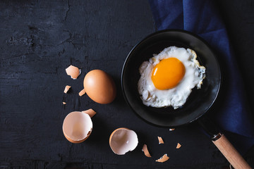 Top view of Cooking Fried egg In the pan on black background