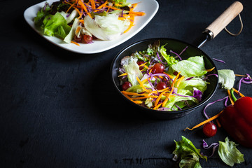 .Bowl of vegetable salad on black background.