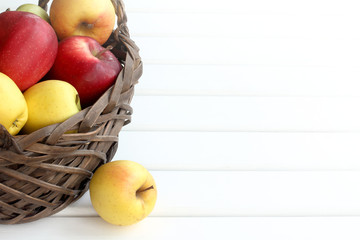many multi-colored apples in a wicker basket on the table front view. autumn fruit harvest