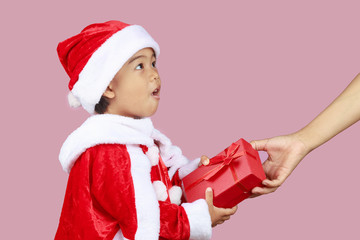 Portrait of Asian cute girl wearing santa costumes giving red gift box with copy space isolated on pink background. christmas concept.