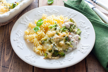 Baked broccoli with chicken on a plate with pasta on a wooden table, selective focus