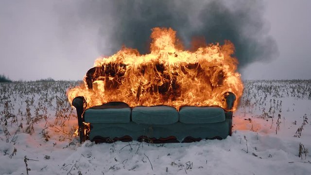 A sofa burns in the field. Conceptual video. Accelerated video
