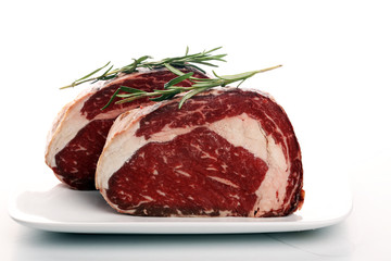Raw fresh meat Ribeye Steak, seasoning and meat fork on rustic background