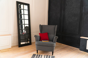 gray armchair with red pillow and blue book