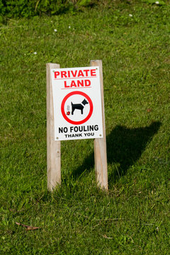 Hinweis Schild auf dem Rasen, Hunde hier nicht scheißen, mit der englischen Aufschrift PRIVATE LAND No fouling Thank you