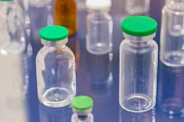 Close up view - pharma industry, science, medicine, experiment, chemistry, research and healthcare concept. Medical empty glass bottles in showcase at pharmaceutical exhibition, pharmacy laboratory