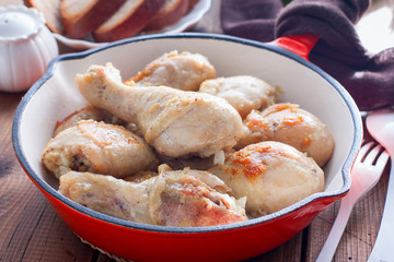 Fried chicken drumsticks in a pan on a wooden table, selective focus