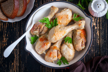 Fried chicken drumsticks in a pan on a wooden table, top view, selective focus