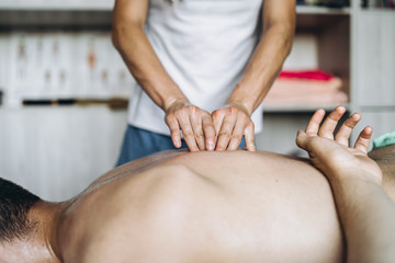 Fototapeta na wymiar Female masseuse gives back massage to man who is lying on massage couch