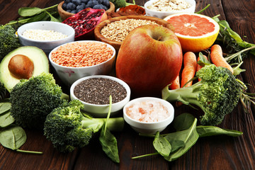 Healthy food clean eating selection: fruit, vegetable, seeds, superfood, cereals, leaf vegetable on rustic background
