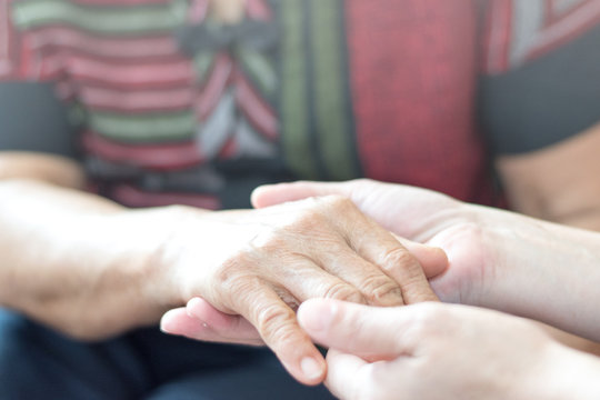 Parkinson and Alzheimer female senior elderly patient with caregiver in hospice care. Doctor hand with stethoscope check up older woman people. Old aging person seeing medical physician in hospital.