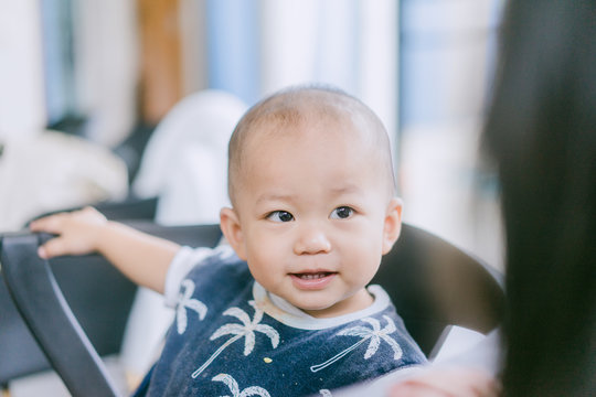 Asian baby boy sitting on dinner table and laughing looking to his sister.