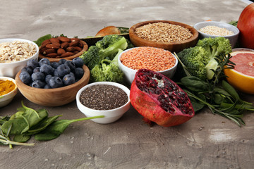 Healthy food clean eating selection: fruit, vegetable, seeds, superfood, cereals, leaf vegetable on rustic background