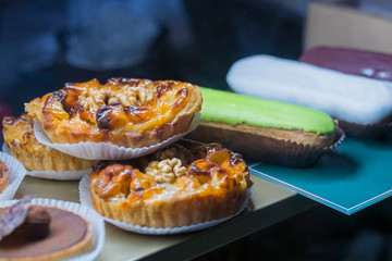 Assortment of delicious fresh shortcrust tart cakes with cream and walnut for sale on counter of shop, grocery, market, cafe or bakery. Dessert, sweet food and confectionery concept