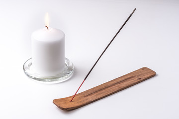Incienso y vela de cera encendida sobre fondo blanco