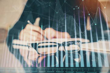 Forex chart hologram on hand taking notes background. Concept of analysis. Multi exposure