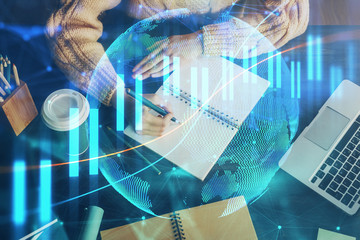 Forex graph on hand taking notes background. Concept of research. Double exposure