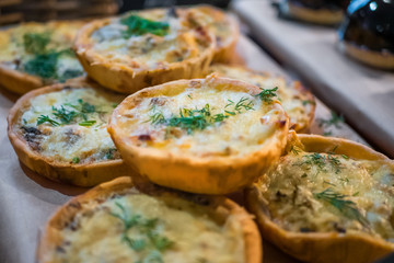 Close up view - assortment of delicious freshly baked tart pies with cheese, meat, mushroom and dill for sale on counter of shop, grocery, market, cafe or bakery. Food, gastronomy and pastry concept