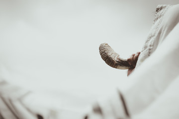 Jewish man in Tallit blowing the Shofar (horn) of Rosh Hashanah (New Year Jew) and Yom Kippur...