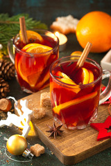 Winter Christmas mulled wine with orange and spices on the festive table.