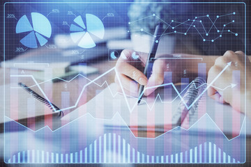 Financial forex graph drawn over hands taking notes background. Concept of research. Multi exposure