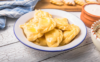 Ukrainian dumplings, pierogi or pyrohy, varenyky, vareniki, served with cottage cheese on board. National Russian cuisine, natural organic homemade bakery product, view from above.