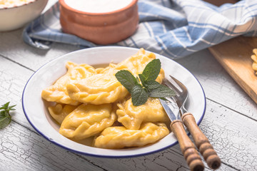 Ukrainian dumplings, pierogi or pyrohy, varenyky, vareniki, served with cottage cheese on board. National Russian cuisine, natural organic homemade bakery product, view from above.