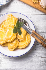 Ukrainian dumplings, pierogi or pyrohy, varenyky, vareniki, served with cottage cheese on board. National Russian cuisine, natural organic homemade bakery product, view from above.