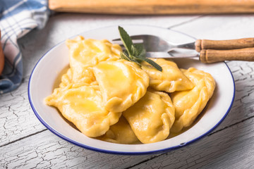 Ukrainian dumplings, pierogi or pyrohy, varenyky, vareniki, served with cottage cheese on board. National Russian cuisine, natural organic homemade bakery product, view from above.