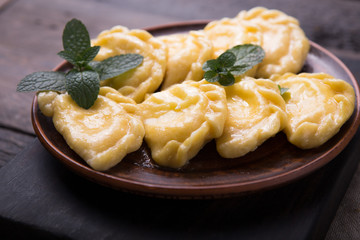 Ukrainian dumplings, pierogi or pyrohy, varenyky, vareniki, served with cottage cheese on board. National Russian cuisine, natural organic homemade bakery product, view from above.