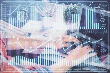 Double exposure of stock graph with businessman typing on computer in office on background. Concept of hard work.
