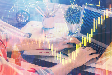 Double exposure of stock graph with businessman typing on computer in office on background. Concept of hard work.