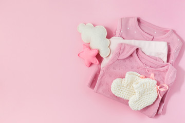 Pink background with clothes, socks and toys for a newborn girl.