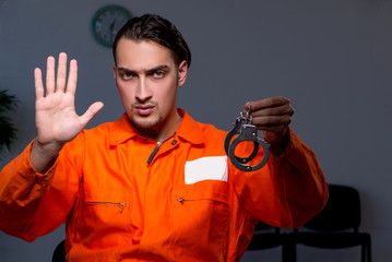 Young convict man sitting in dark room