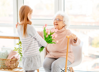 Girl presenting bouquet to old woman