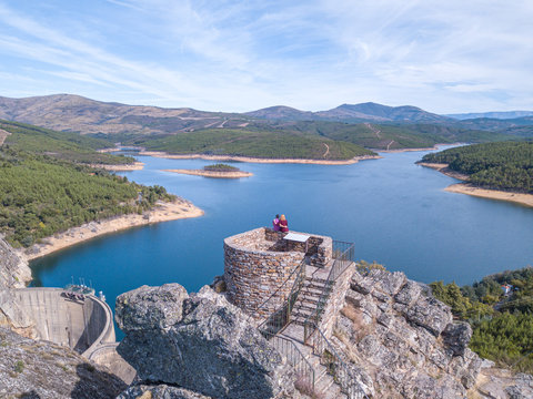 Barragem Santa Luzia dam in Pampilhosa da Serra, Coimbra, Portugal. Aerial view of a tourist couple staring at the dam from a nearest viewpoint.