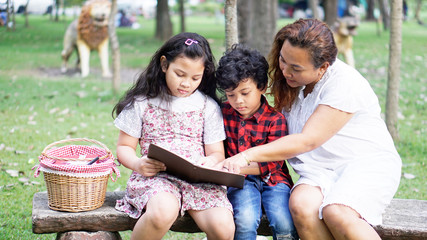 Asian families sit in the garden, read books for their daughter and son holidays, happy mother's day or family holiday.  