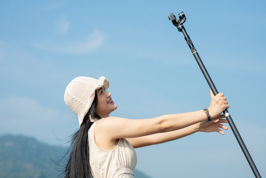 Happy Asian woman using action camera selfie herself with nature view, lifestyle concept.