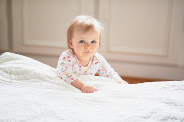 Baby girl playing near bed and laughing