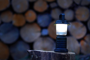 Portable flashlight standing on a wood. Flashlight for camping, fishing or hiking.