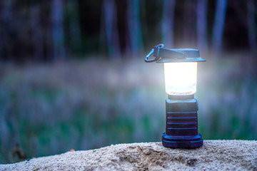 Portable flashlight standing on land of forest. Copy space.