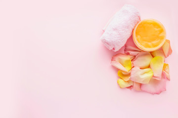 Open jar of cosmetic cream and towel on pink background. Concept of natural spa cosmetics. Flat lay, top view, copy space .