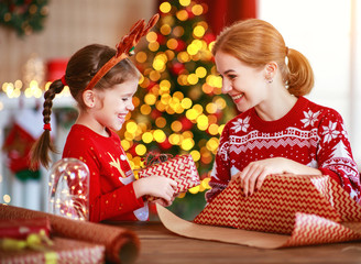 Fototapeta na wymiar happy family mother and child pack Christmas gifts at home near Christmas tree