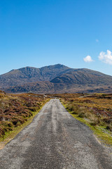 A long single track road on the Hebridean island of South Uist with mountains in the distance