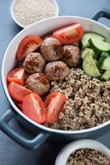 Close-up of a serving pan with fried meatballs, quinoa and vegetables, vertical shot